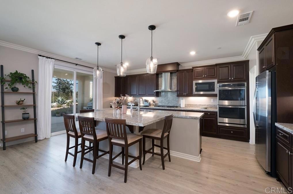33792 Baystone Street Temecula, CA 92592 - Photo 11 of 21 a kitchen with stainless steel appliances granite countertop a stove a refrigerator a kitchen island a table and chairs