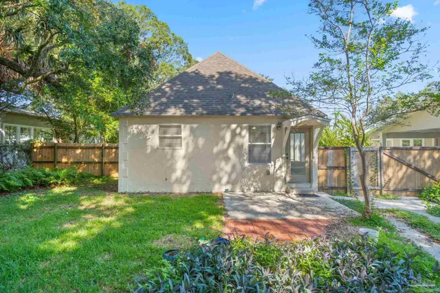 a view of a backyard with large trees and wooden fence