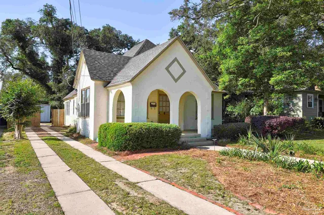 a view of a white house with a yard and large tree