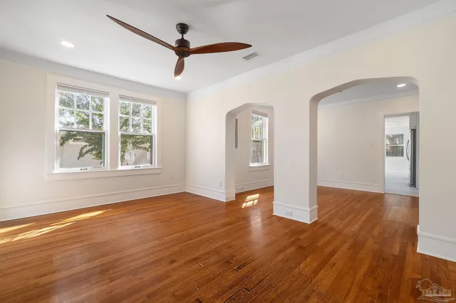 a view of empty room with wooden floor and fan