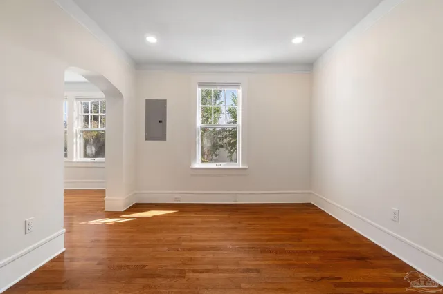 an empty room with wooden floor and windows