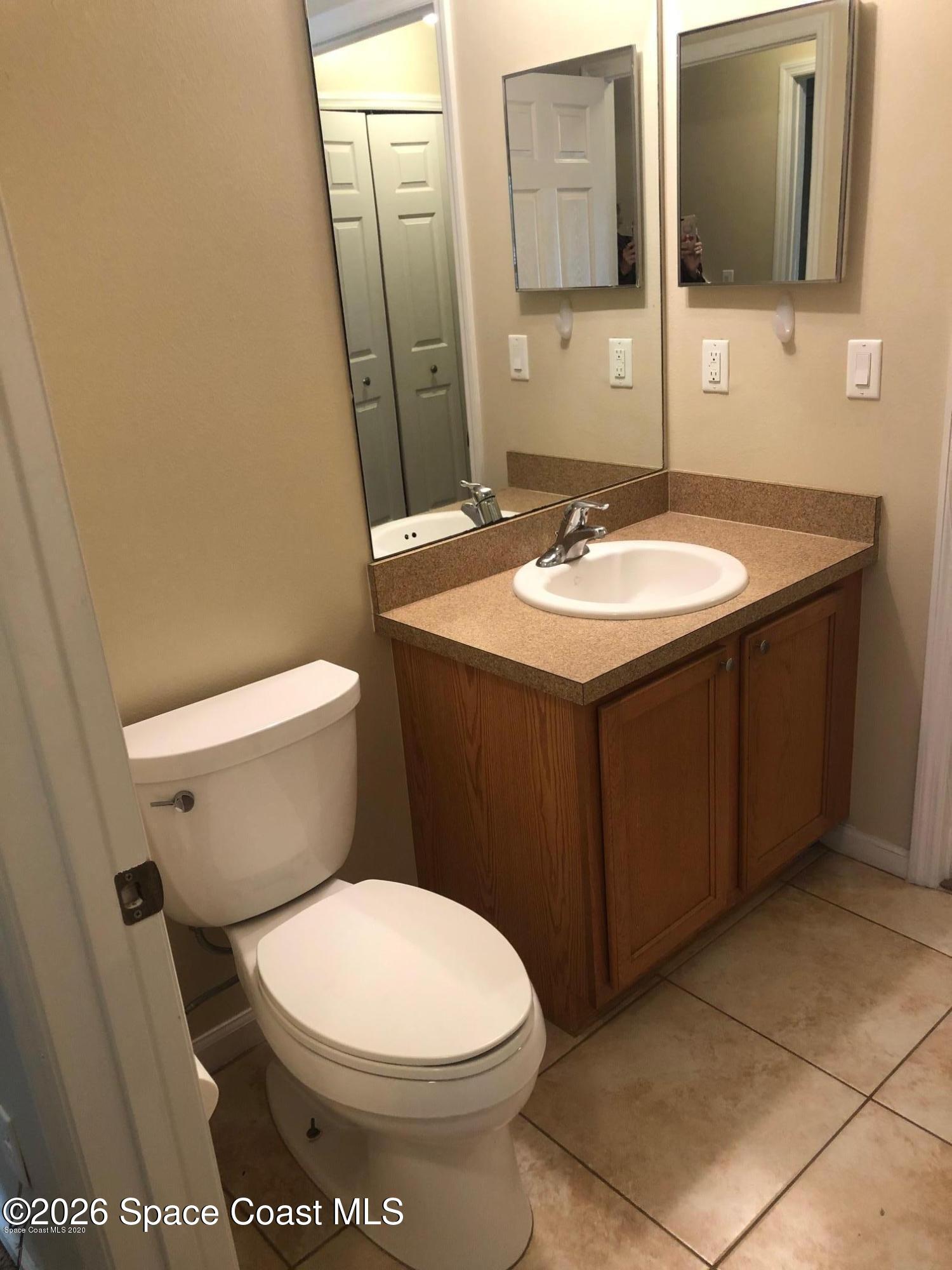 1280 Luminary Circle, Unit 103 Melbourne, FL 32901 - Photo 11 of 14 a bathroom with a sink a toilet and mirror
