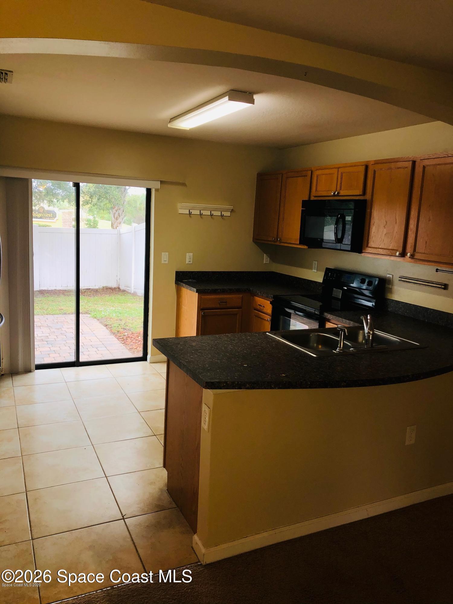 1280 Luminary Circle, Unit 103 Melbourne, FL 32901 - Photo 4 of 14 a kitchen with stainless steel appliances granite countertop a stove a sink and a microwave