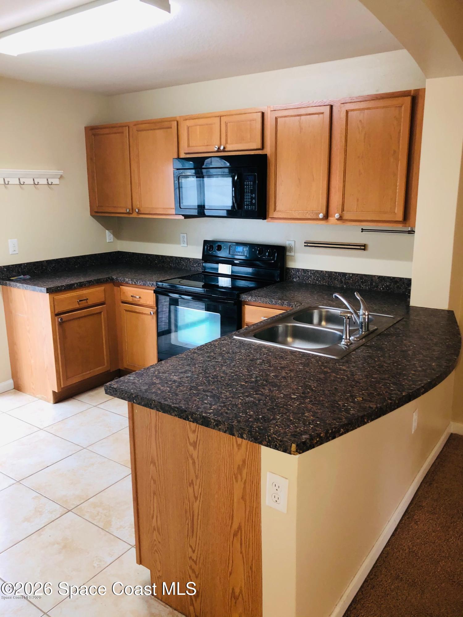 1280 Luminary Circle, Unit 103 Melbourne, FL 32901 - Photo 5 of 14 a kitchen with stainless steel appliances granite countertop a sink a stove and a microwave