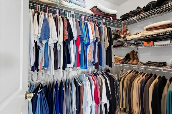 a view of walk in closet with clothes and shoes