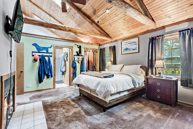 a bedroom with a bed table fireplace and a window