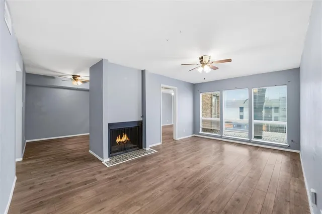 a view of an empty room with wooden floor fireplace and a window