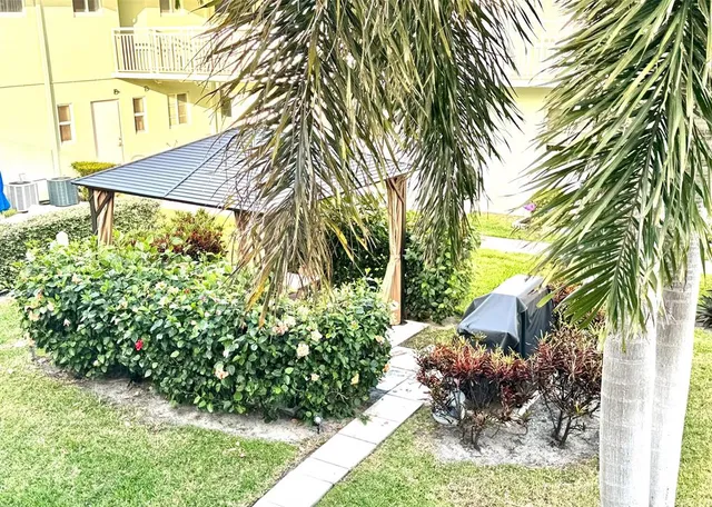 a view of a white house with a yard and plants