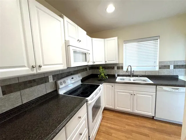 a kitchen with granite countertop white cabinets and stainless steel appliances