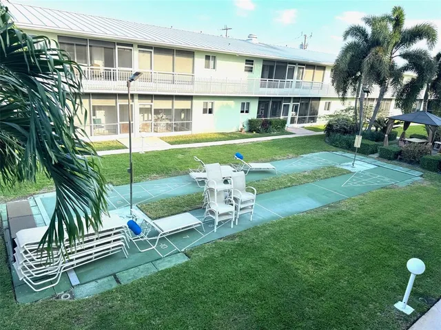 a backyard of a house with table and chairs under an umbrella