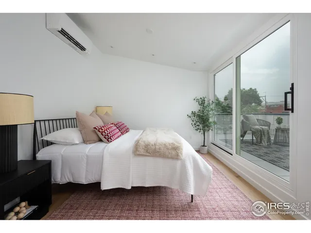 a bedroom with a bed lamp mirror and window