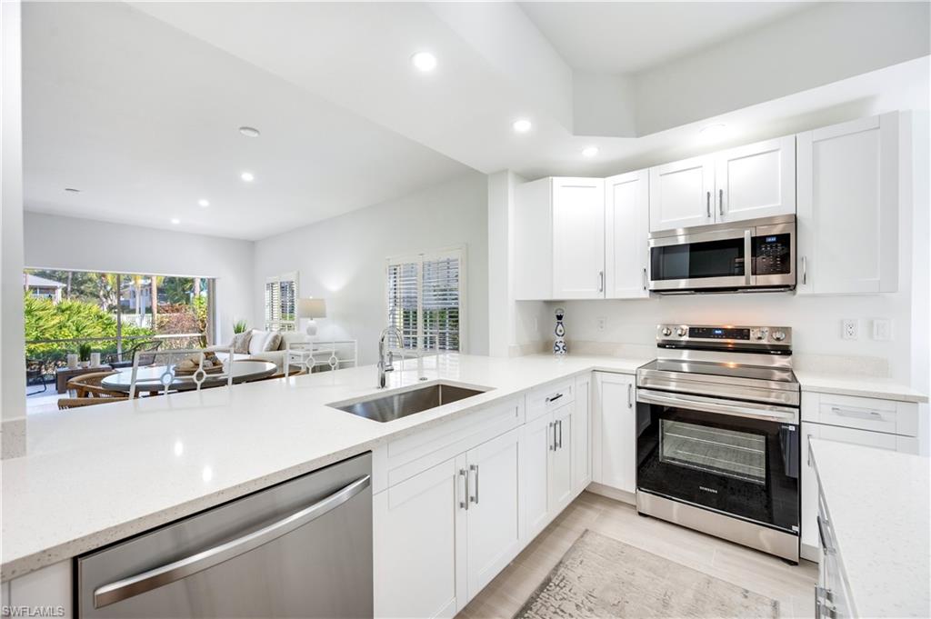 2806 Aintree Lane, Unit H102 Naples, FL 34112 - Photo 26 of 26 Kitchen featuring appliances with stainless steel finishes, white cabinetry, recessed lighting, light stone countertops, and open floor plan