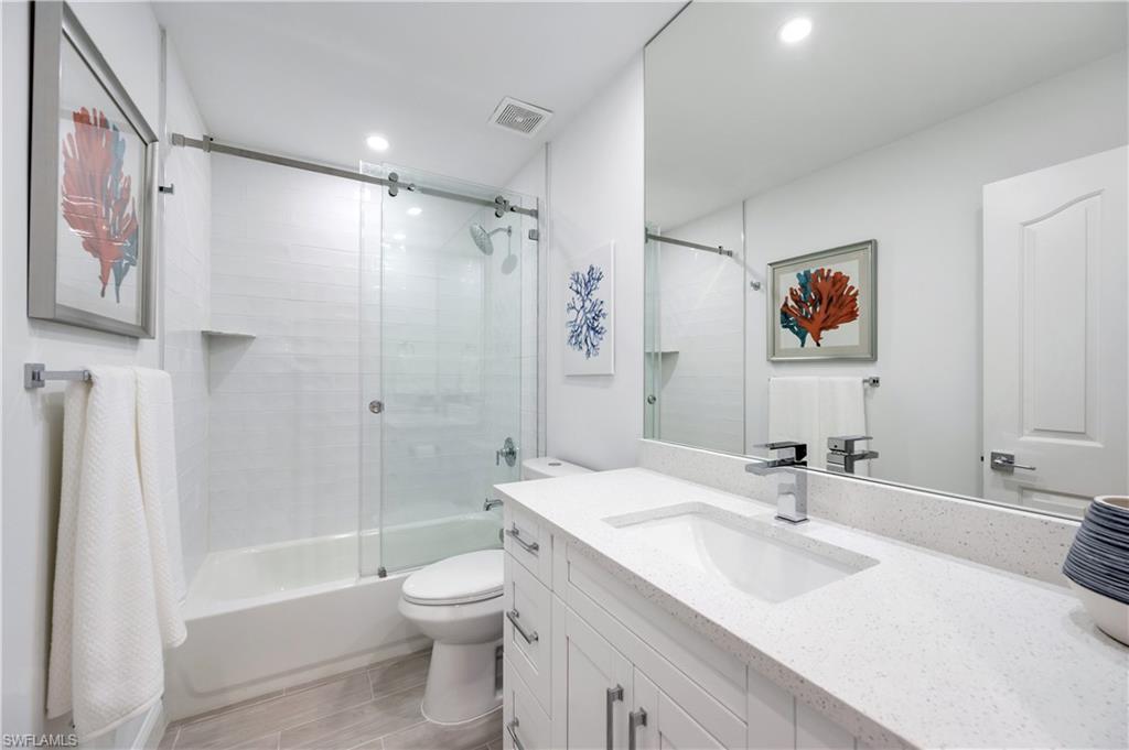 2806 Aintree Lane, Unit H102 Naples, FL 34112 - Photo 18 of 26 Bathroom featuring shower / bath combination with glass door, vanity, and wood finish floors