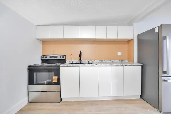 a kitchen with white cabinets and appliances