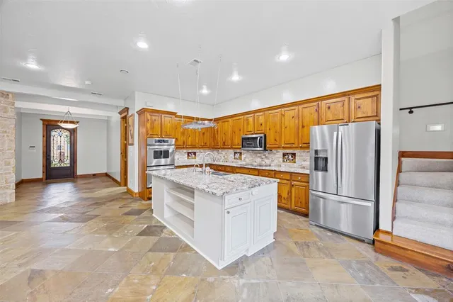 a kitchen with stainless steel appliances granite countertop a refrigerator and a stove top oven