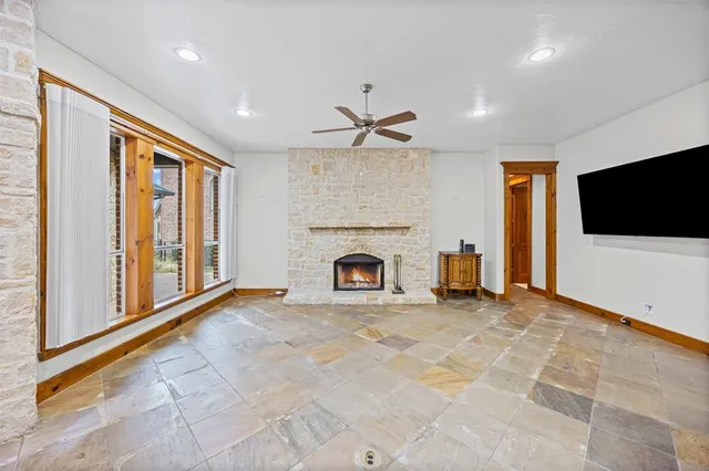 a view of a livingroom with a fireplace a ceiling fan and windows