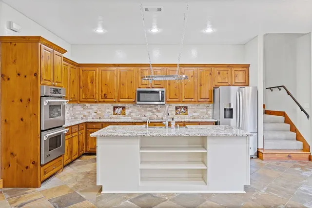 a kitchen with stainless steel appliances granite countertop a sink and a refrigerator