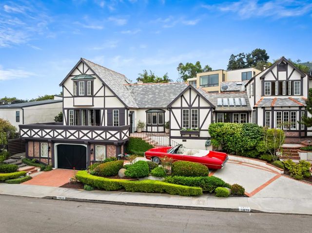 a front view of a house with a yard and potted plants
