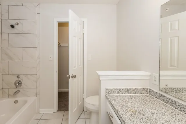 a bathroom with a granite countertop bathtub and a toilet