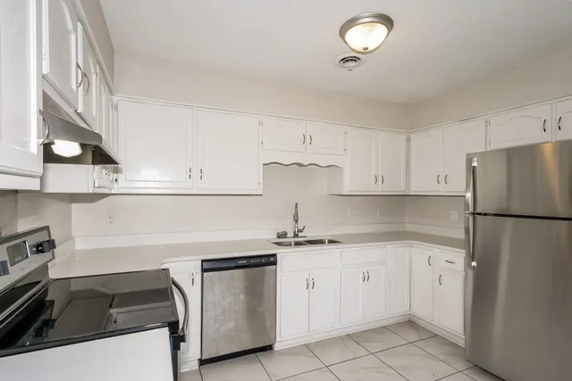 a kitchen with white cabinets and appliances