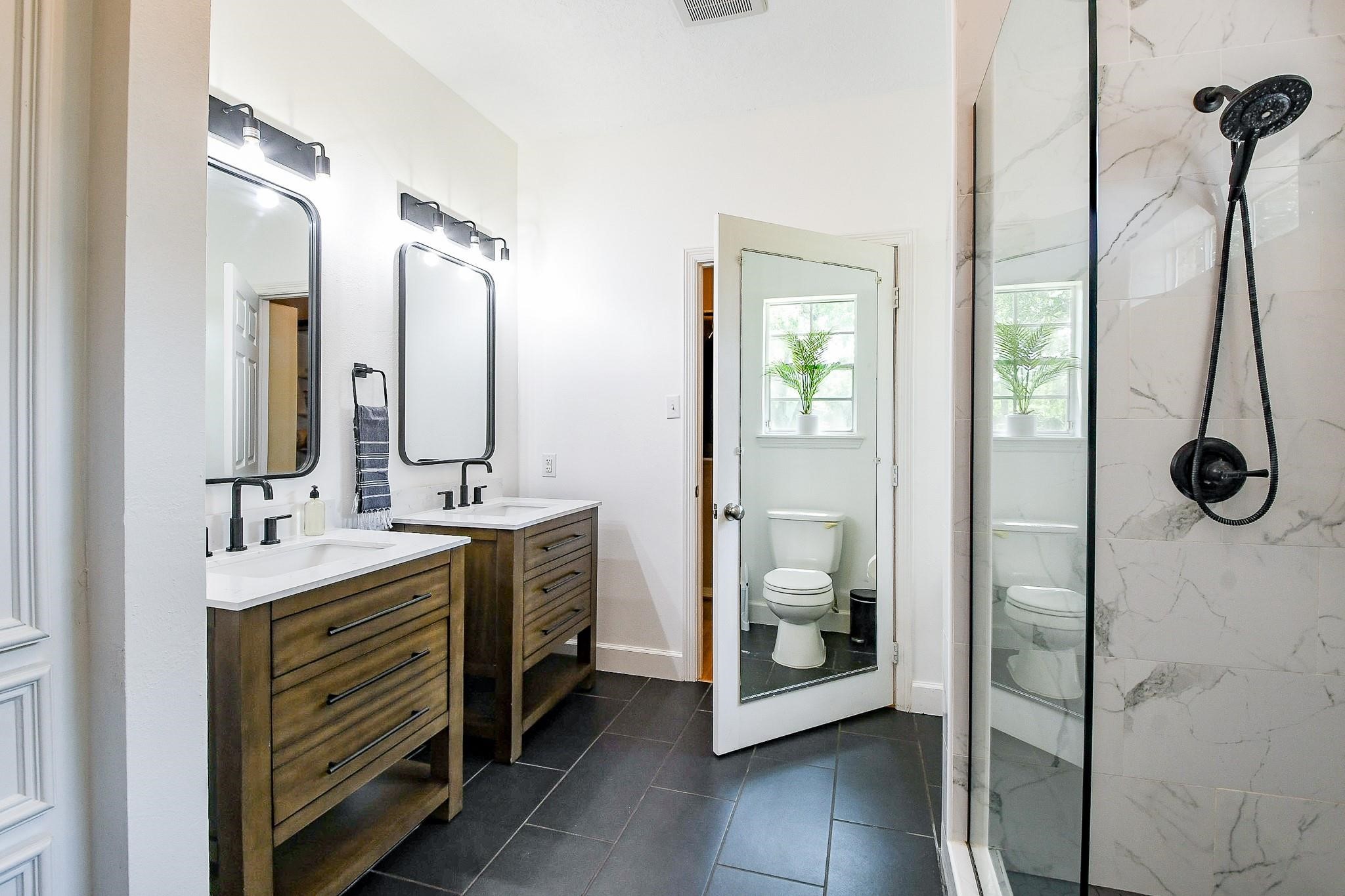 22035 Buescher Road Tomball, TX 77377 - Photo 23 of 44 a bathroom with a double vanity sink a mirror and a shower