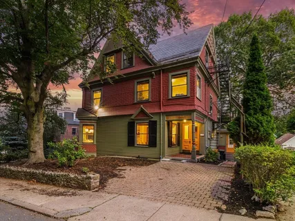 a view of a brick house with large windows and a small yard