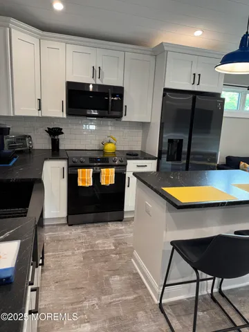 a kitchen with stainless steel appliances a stove a sink a microwave a refrigerator and cabinets