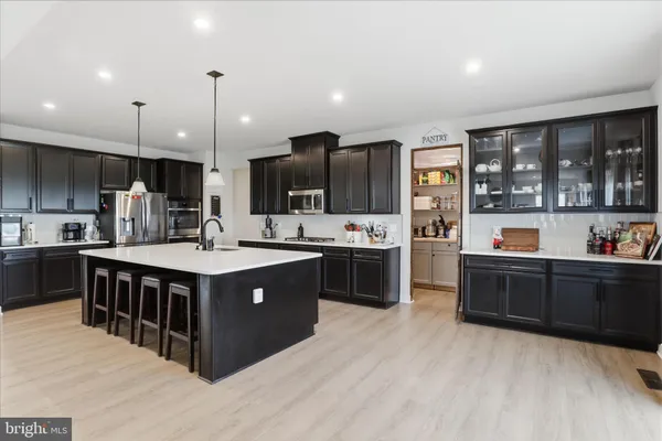 a view of a kitchen with kitchen island a sink stainless steel appliances and cabinets