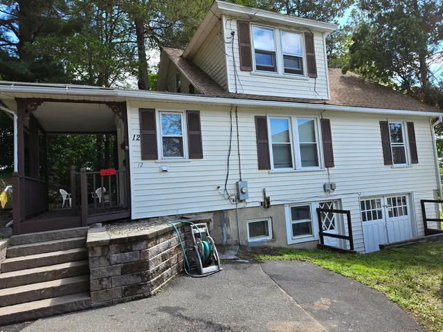 a view of a house with a small yard and a large tree