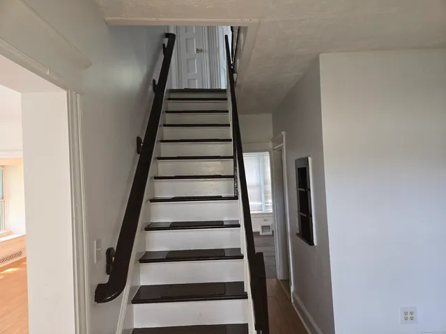 a view of staircase with wooden floor and white walls