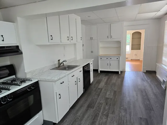 a kitchen with stainless steel appliances a white stove top oven cabinets and a wooden floor