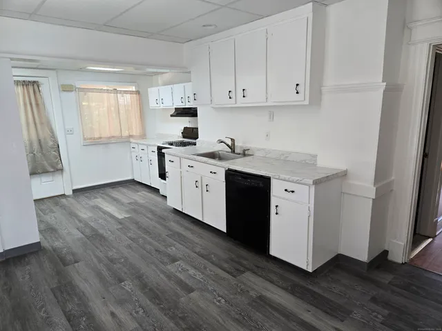 a kitchen with stainless steel appliances granite countertop a stove a sink and white cabinets with wooden floor