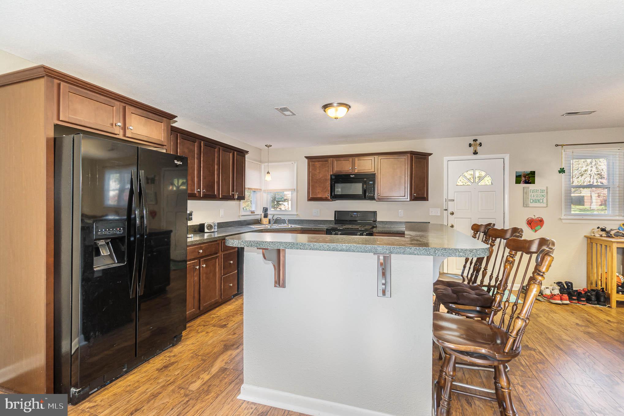 404 Beaumont Road York, PA 17403 - Photo 6 of 26 a kitchen with stainless steel appliances kitchen island granite countertop a refrigerator a stove a sink a dining table and chairs with wooden floor