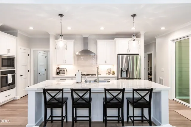a kitchen with stainless steel appliances a dining table chairs and white cabinets