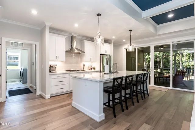 a kitchen with stainless steel appliances granite countertop a table chairs sink and cabinets