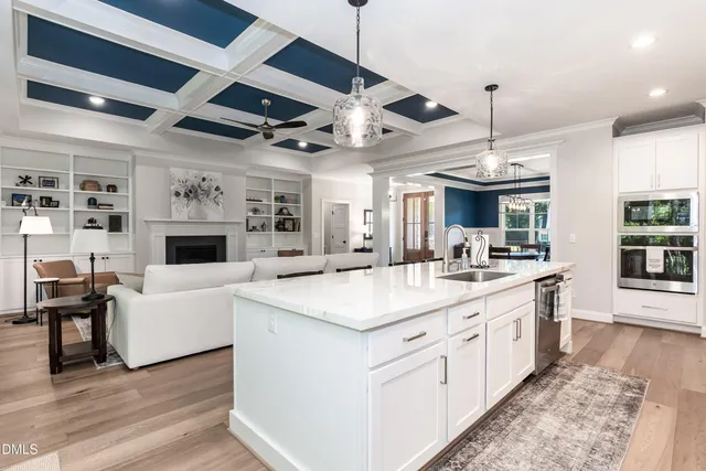 a large white kitchen with a large island oven a stove and a wooden floors
