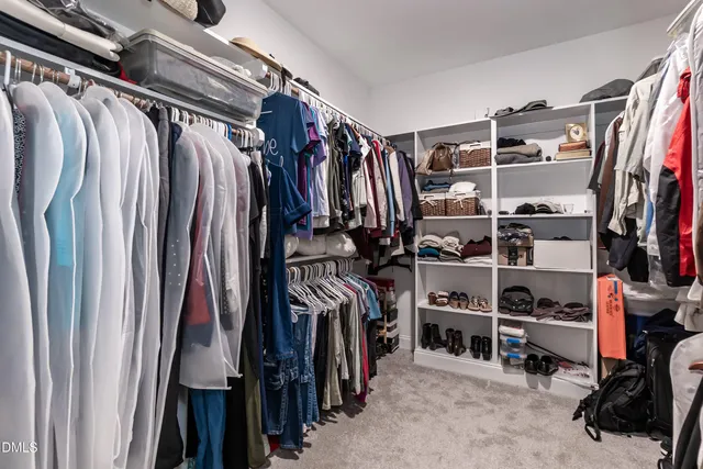 a view of walk in closet with clothes and shoes