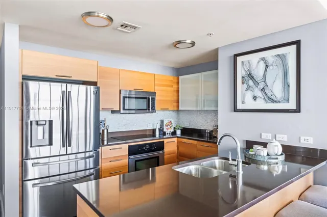 a kitchen with stainless steel appliances granite countertop a refrigerator a sink dishwasher a stove and white countertops with wooden floor