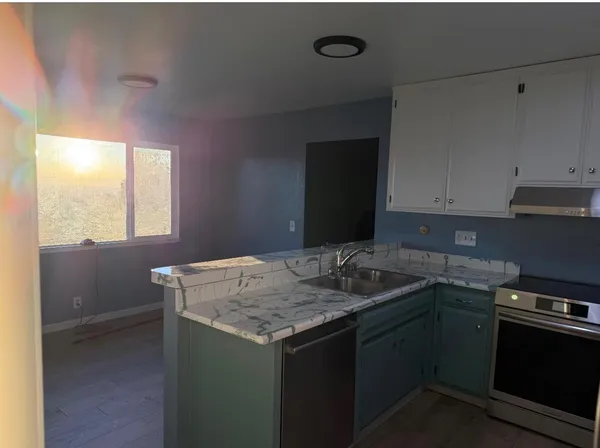 a kitchen with kitchen island granite countertop a sink a stove and refrigerator