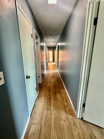 an empty room with wooden floor fireplace and windows