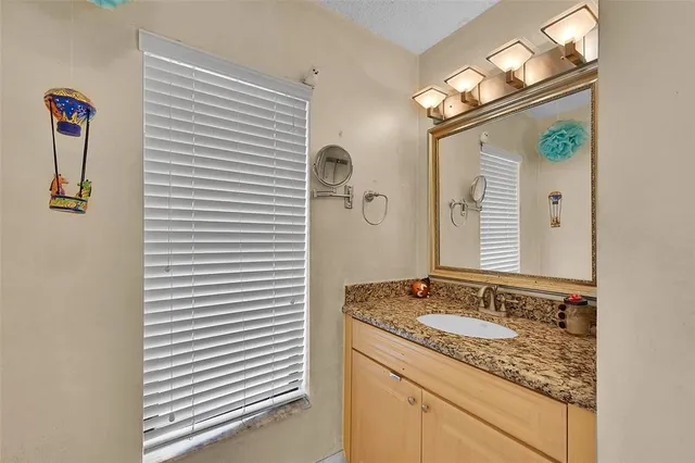 a bathroom with a granite countertop sink and a mirror