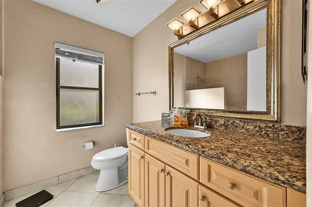 a bathroom with a granite countertop toilet sink and mirror