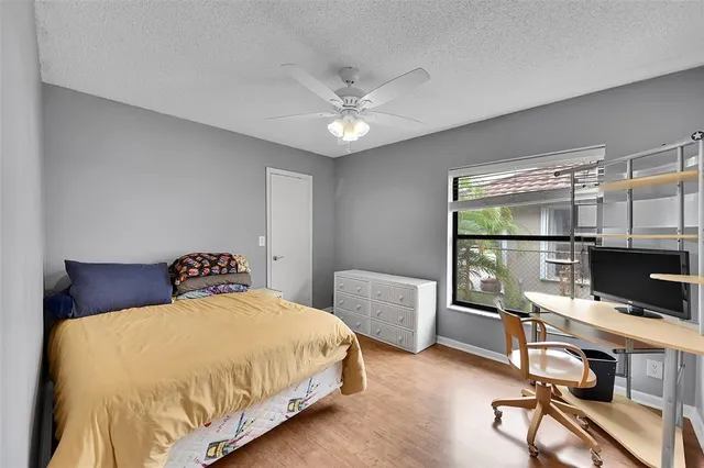 a bedroom with a bed a desk and chair with floor to ceiling window
