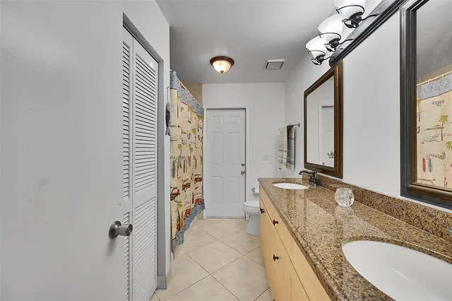 a bathroom with a granite countertop double vanity sink a mirror and a shower