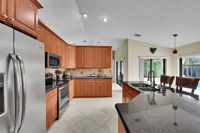a kitchen with stainless steel appliances granite countertop a refrigerator stove top oven dining table and chairs