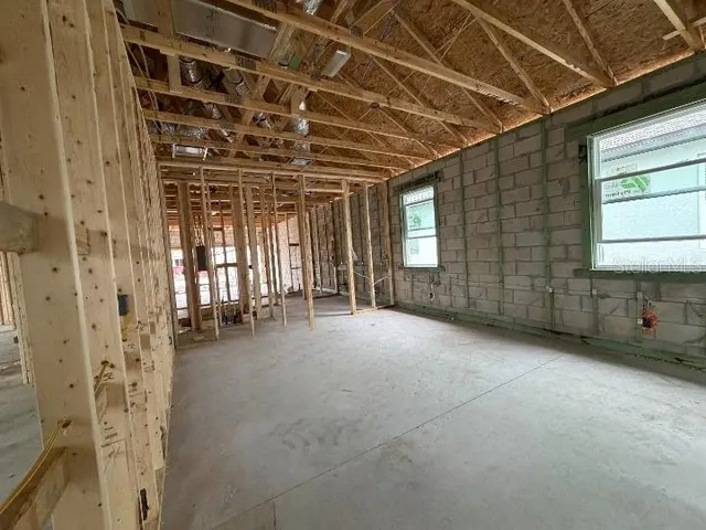 a view of an empty room with wooden floor and windows