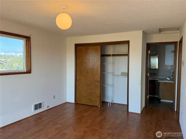 an empty room with wooden floor and closet