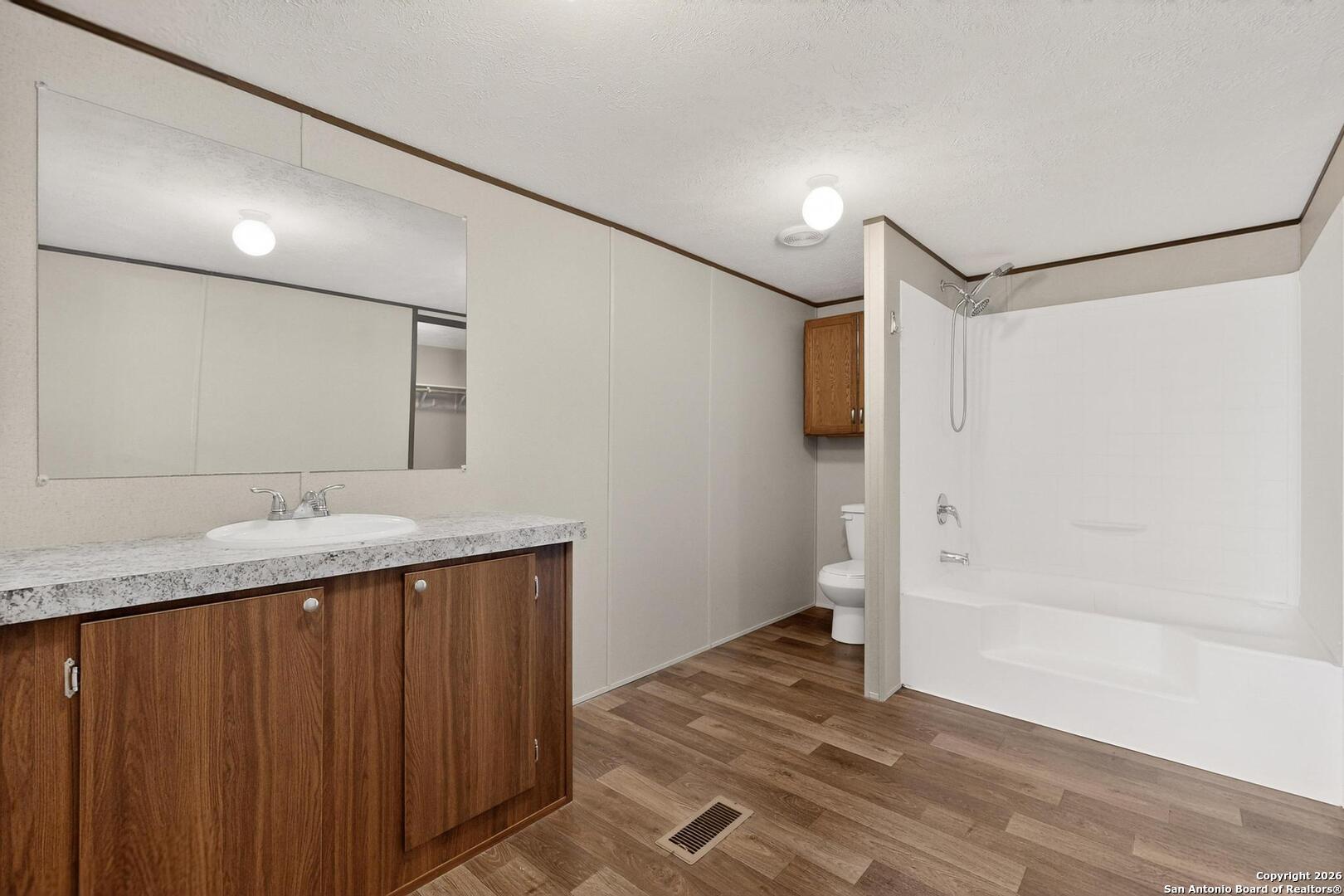 19124 La Gloria Road Elmendorf, TX 78112 - Photo 19 of 45 a bathroom with a granite countertop sink and a mirror