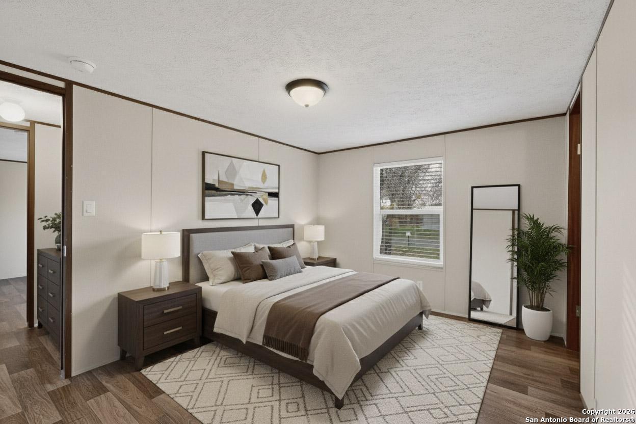 19124 La Gloria Road Elmendorf, TX 78112 - Photo 31 of 45 a bedroom with a large bed and a chandelier