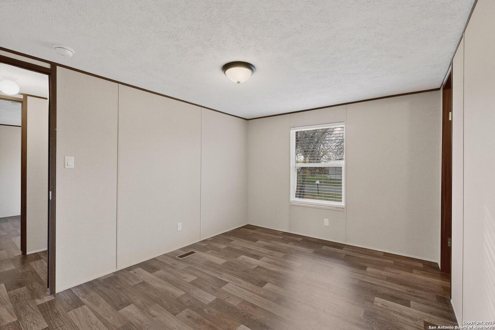 19124 La Gloria Road Elmendorf, TX 78112 - Photo 32 of 45 an empty room with wooden floor and windows